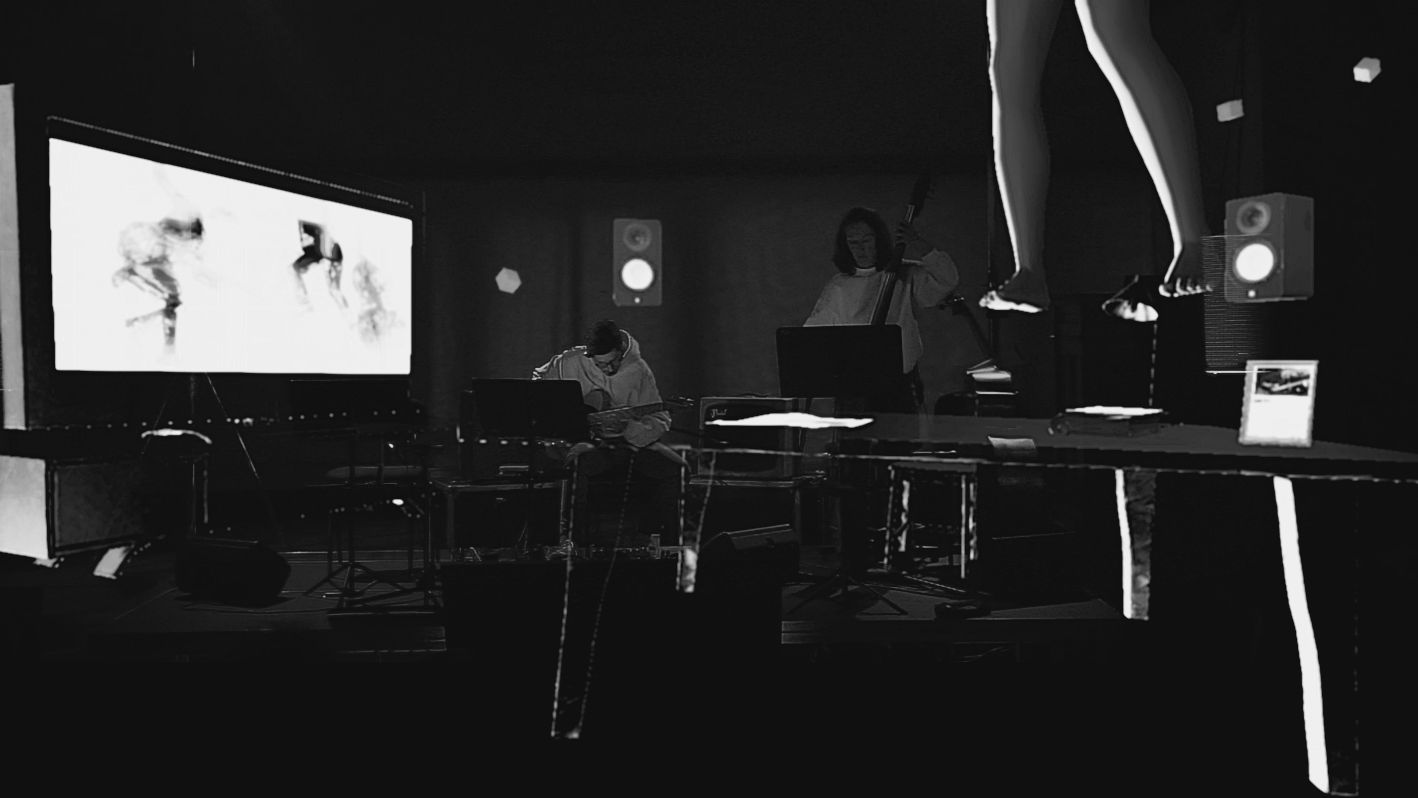General view of RêVeRie: a projection screen, musicians with a double bass, loudspeakers and a long table in a dark room.